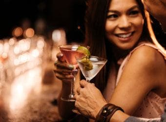 Single woman sharing a cocktail with her date in a bar.